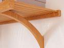 Close-up of a John Louis Home wooden shelf supported by a decorative, curved wooden angle bracket mounted on a textured white wall, showcasing fine details.