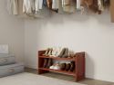 A neatly organized closet with a variety of shoes easily accessible on a solid wood shoe rack and clothes hanging on the wall.