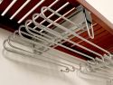 A closeup view of how a John Louis Home metal pants hanger is attached to the underside of a solid wood shelf