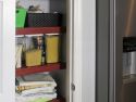 A small neatly organized pantry with wire shelf covers in a kitchen next to a refridgerator 