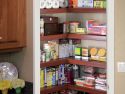 An open pantry door revealing neatly arranged shelves using wire shelf covers stocked with various food items and kitchen essentials to create a updated modern style that matches the kitchen cabinetry.