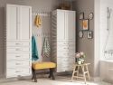 
A tidy and coordinated bathroom interior featuring John Louis Home solid wood storage towers a wooden bench with a yellow cushion, and decorative items on a small table, like a potted plant and books.