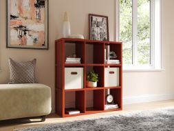 Interior of a living room featuring a couch, chair, and a 9 cube storage organizer with cream storage bins, decor items and books.