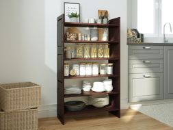 A organized 3 tiered shoe and shelving storage rack that is in a kitchen filled with various jars of pasta, spices, plates and cutlery creating a very neat and tidy storage solution. 