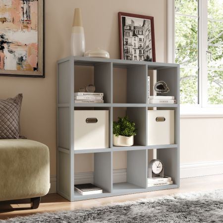 Interior of a living room featuring a couch, chair, and an 9 cube storage organizer with cream storage bins, decor items and books.
