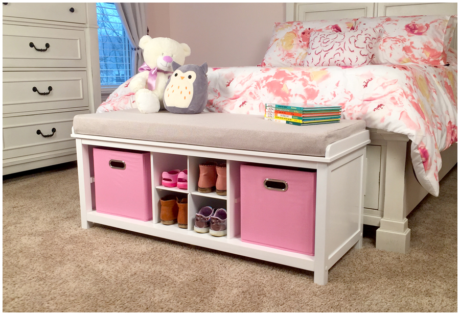 A child's bedroom with a bench at the end of the bed with shoe storage and fabric storage bins.