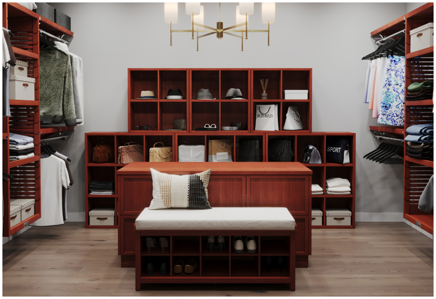 A well-lit walk-in closet with a wooden bench with a cushioned top. Behind the bench is a shelf with clothes and shoes.